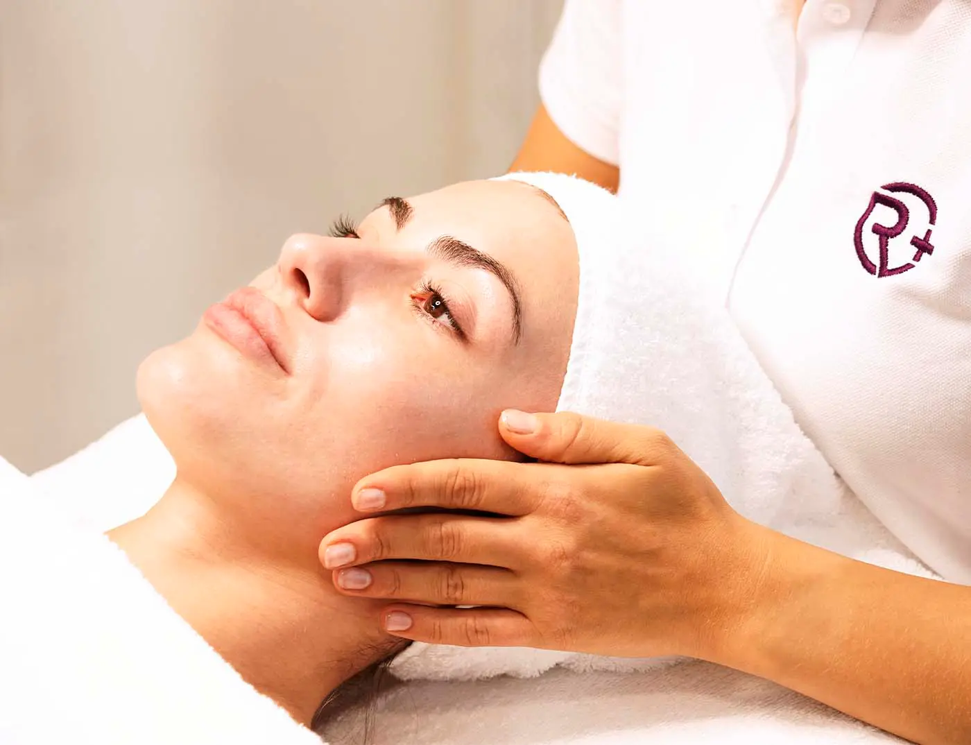 Kosmetikern hält das Gesicht einer jungen Kundin