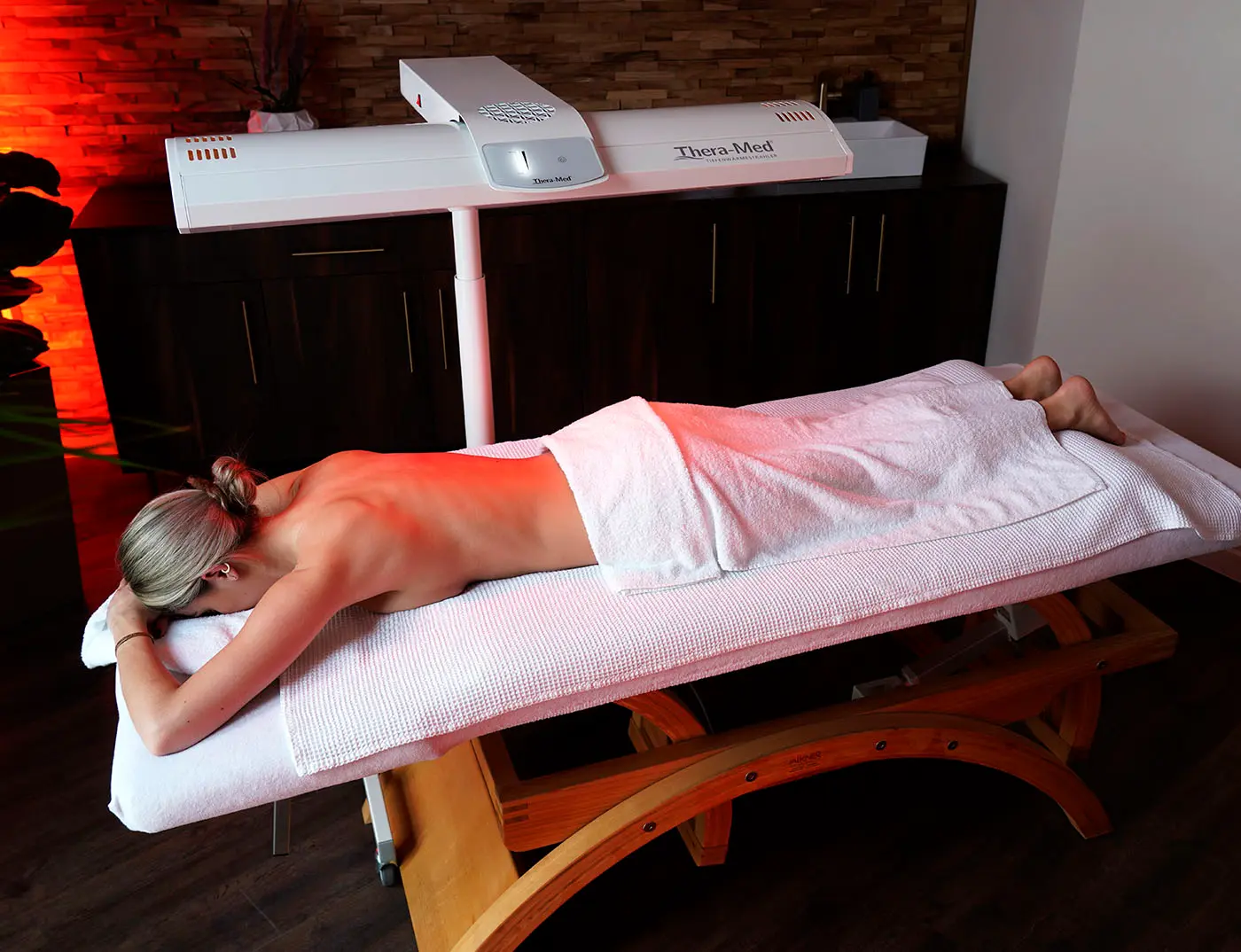 Frau auf dem Bauch liegend bei Rotlicht Therapie bei Relax plus