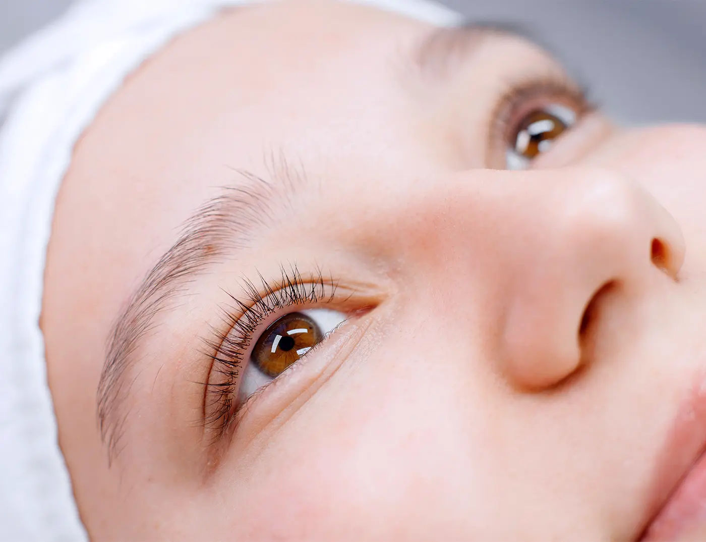 Frau mit braunen Augen blickt nach einem Wimpernlifting nach oben