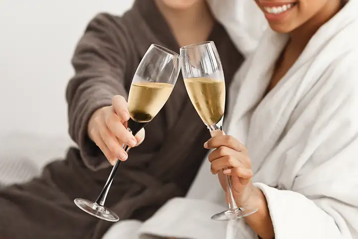zwei Frauen im Bademantel halten ein Glas Sekt